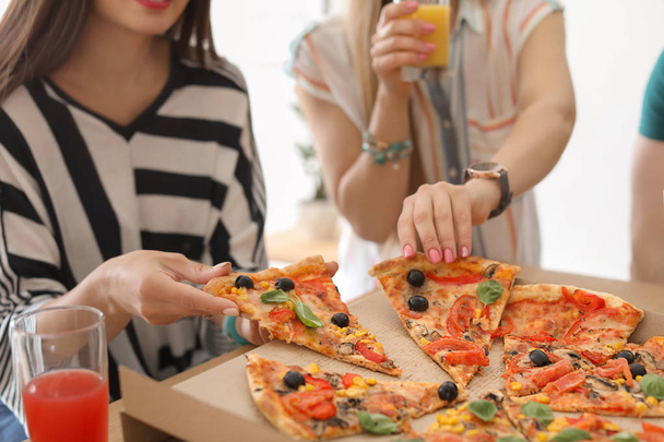 Young people eating delicious pizza at table, closeup - Fotó, kép