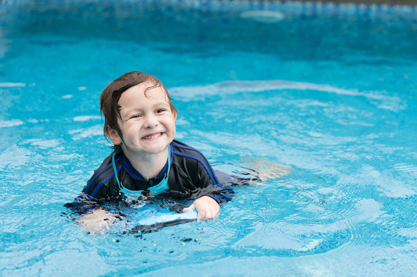 Boy playing in outdoor swimming pool. Kids  practicing swim with foam pad. - Photo, Image