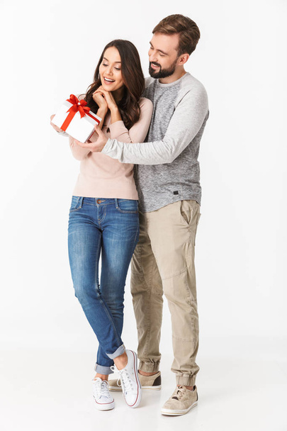 Image of excited young loving couple isolated over white wall background holding gift present box. - Valokuva, kuva