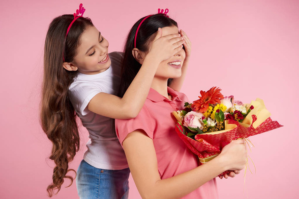 Nice little daughter gives flowers to beautiful - 写真・画像