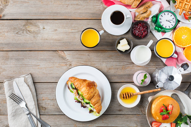 Étel és ital, az egészséges reggeli étkezési koncepció. Reggeli választék, palacsinta, gofri, szendvics kifli és granola joghurttal, a fából készült asztal. Top Nézd lapos laikus háttér - Fotó, kép