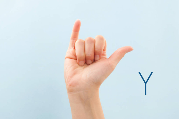 American sign language. Female hand showing letter Y isolated on blue background.  - Photo, Image