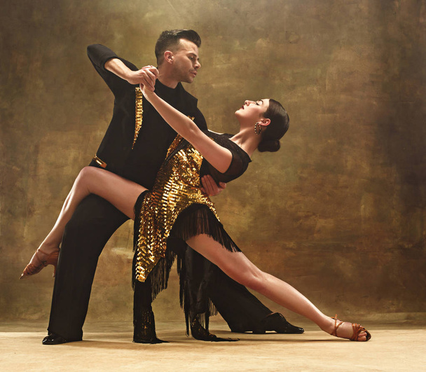 Dance ballroom couple in gold dress dancing on studio background. - Foto, afbeelding