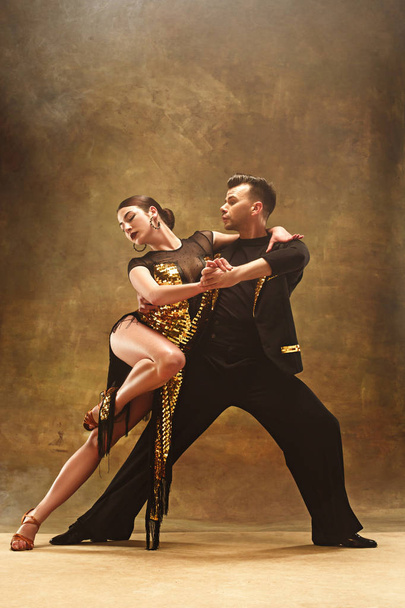 Dance ballroom couple in gold dress dancing on studio background. - Фото, зображення