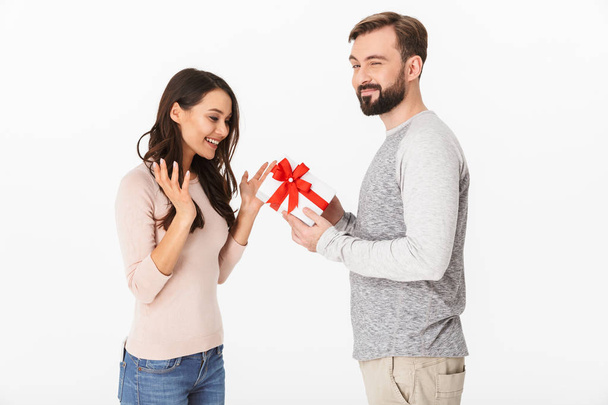 Image of happy young man standing with surprise box for his woman isolated over white background wall. - Zdjęcie, obraz
