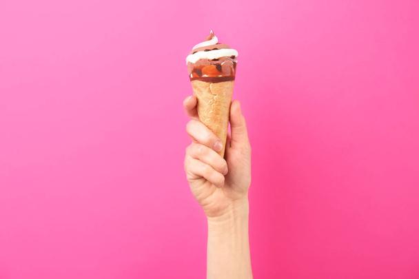 Woman holding yummy ice cream on color background. Focus on hand - Fotoğraf, Görsel