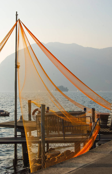 Redes de pesca unidas a un poste con panorama del lago Iseo
 - Foto, imagen
