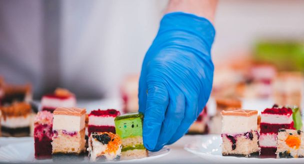 Close view of confectioner putting cakes on plates in pastry shop - Фото, зображення