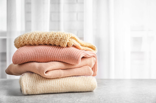 Stack of warm knitted clothes on table - Φωτογραφία, εικόνα