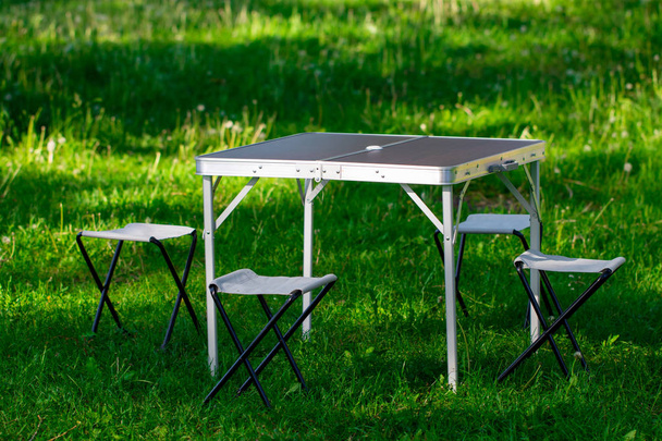 schöner Picknickplatz mit Tisch und Hockern auf dem Rasen. - Foto, Bild