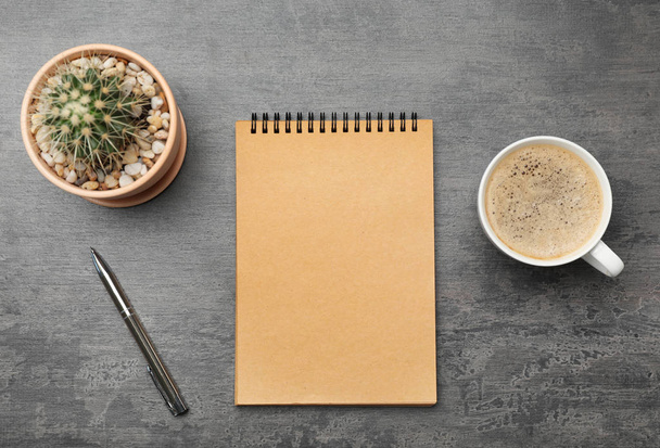 Flat lay composition with notebook and cup of coffee on grey background - Photo, image