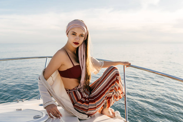young beautiful girl in stylish summer clothes sits on a white yacht, went on a sea voyage, on vacation - Foto, immagini