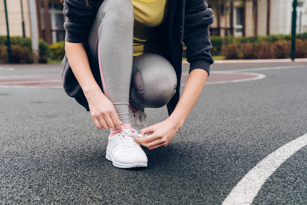 молода струнка дівчина зав'язує взуття на кросівки, займається спортом і веде здоровий спосіб життя
 - Фото, зображення