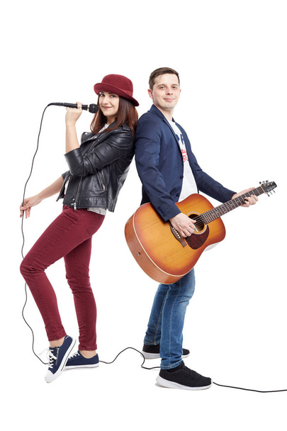 A musical duo of a young couple, a singer in a red hat with a microphone and a handsome guy in a blue jacket with an acoustic guitar. Isolated on white background. - Фото, зображення