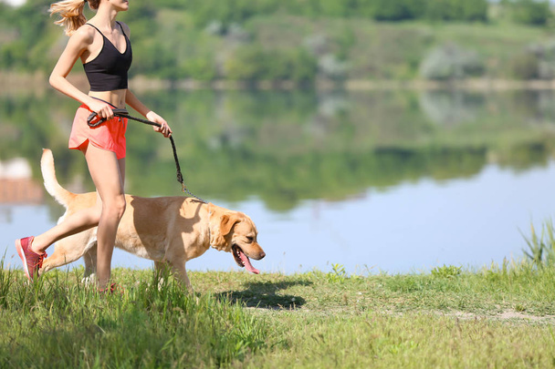 Young woman and her dog spending time together outdoors. Pet care - Zdjęcie, obraz