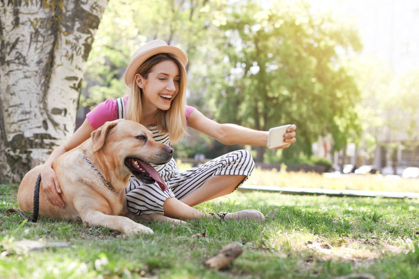 Young woman taking selfie with her dog outdoors. Pet care - Fotó, kép