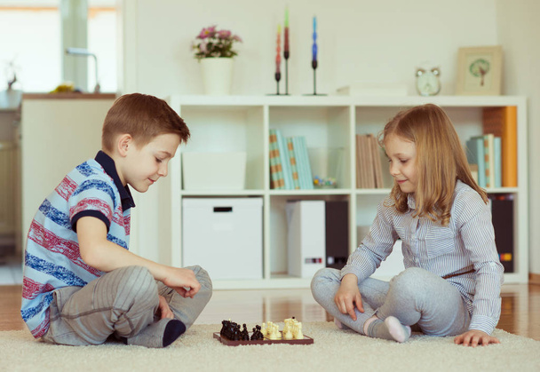 Two little children playing chess at home  emotionally - Foto, imagen