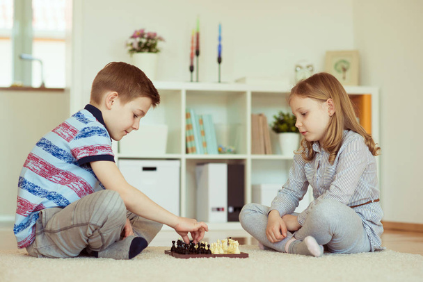 Due bambini piccoli che giocano a scacchi a casa emotivamente
 - Foto, immagini