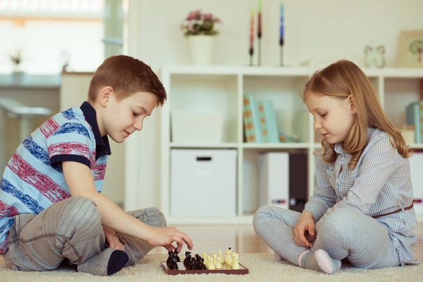 Two little children playing chess at home  emotionally - Фото, зображення