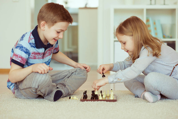 Двое маленьких детей играют в шахматы дома эмоционально
 - Фото, изображение