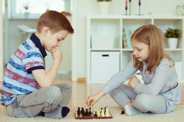 Portrait of two little children concentrated playing chess at home   - Foto, Imagem