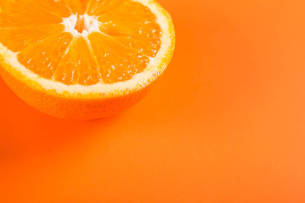 Turuncu renkli arka plan üzerinde yarım turuncu meyve üstten görünüm - Fotoğraf, Görsel
