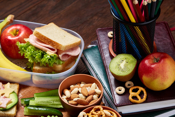 School or picnic lunch box with sandwich and various colorful vegetables and fruits on wooden background, close up. - 写真・画像