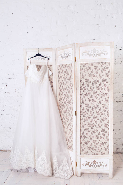 Hochzeitskleid hängt an einem schönen dekorativen Schild. - Foto, Bild
