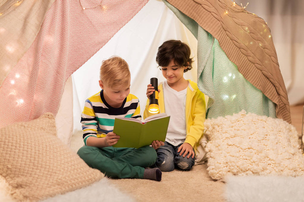happy boys reading book in kids tent at home - Фото, изображение