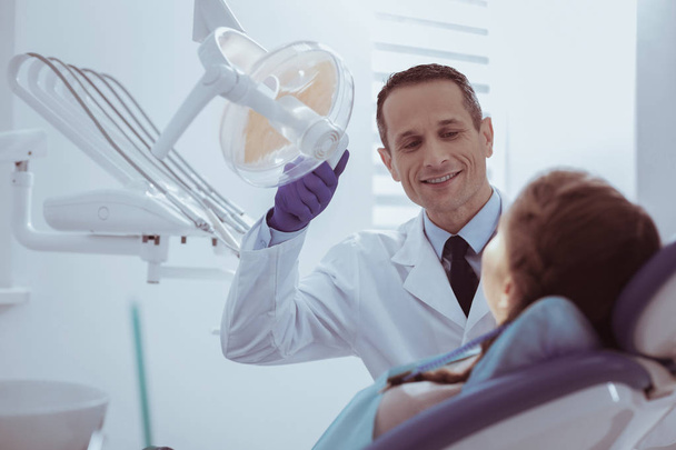 Joyful male dentist verifying oral clean - Фото, изображение