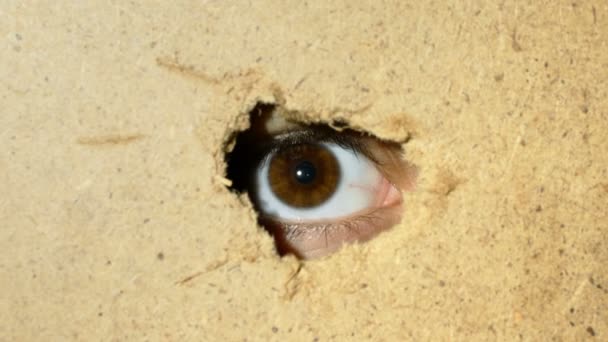 Female oko patrząc przez otwór w ścianie - Materiał filmowy, wideo
