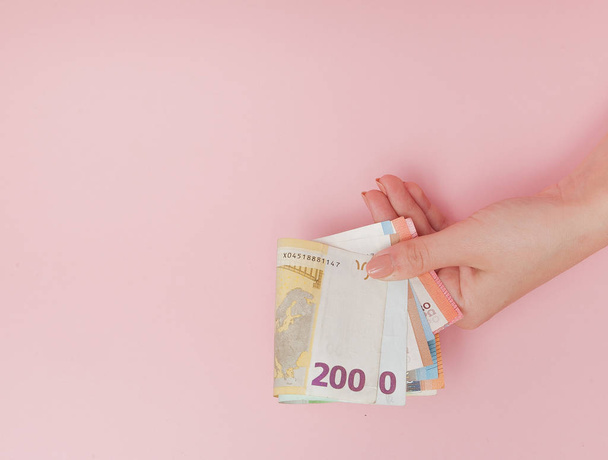 Euro banknotes money in female hands on pink background. Business Concept and Instagram. - Fotó, kép