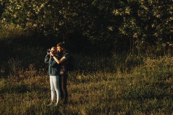 Retrato de larga duración de pareja caucásica increíble aventurándose donde el hombre está enseñando a su novia a fotografiar paisajes contra la luz del sol
. - Foto, imagen