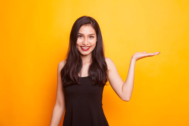 Beautiful young Asian woman show palm hand on yellow background - Foto, Imagem