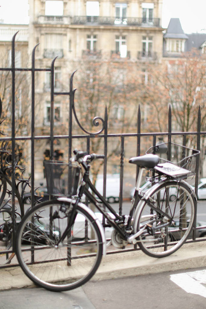 Black bicycle near iron fence with building in background. - Photo, Image