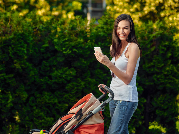 Woman With Baby Carriage Using Cell Phone - Fotoğraf, Görsel