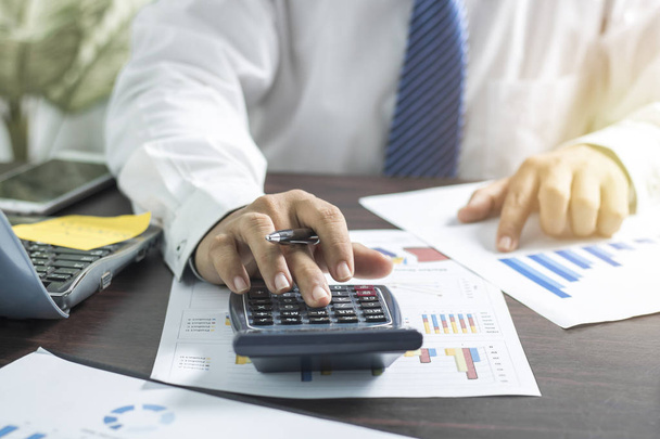 Homme d'affaires poussant et pressant sur la calculatrice et regardant sur le papier d'affaires, concept de finance sur la table de travail
 - Photo, image