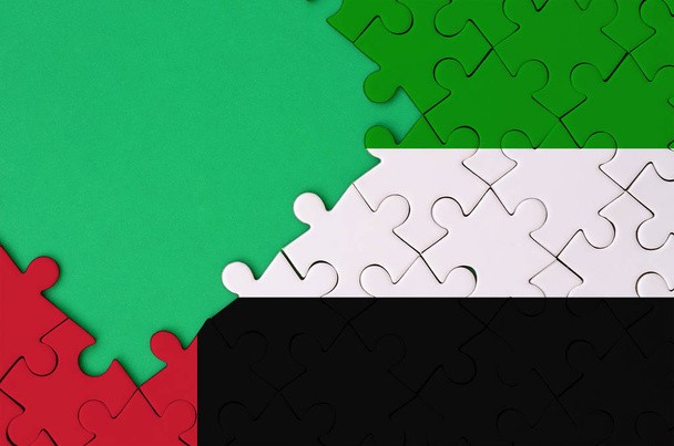 Vlajka Spojených arabských emirátů je zobrazen na dokončené skládačka s bezplatnou zelenou kopii prostoru na levé straně. - Fotografie, Obrázek