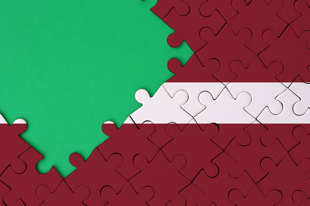 Bandeira da Letónia é representado em um quebra-cabeça completo com espaço livre cópia verde no lado esquerdo
. - Foto, Imagem