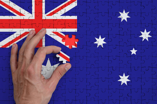 Σημαία Αυστραλίας απεικονίζεται σε ένα παζλ, το οποίο ολοκληρώνει το χέρι του άνδρα να πάει πάσο. - Φωτογραφία, εικόνα