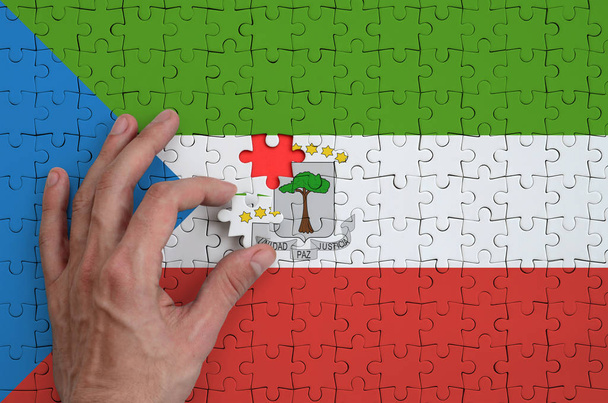 Egyenlítői-Guinea zászló ábrázol egy puzzle, amely az ember keze befejezi a fold. - Fotó, kép