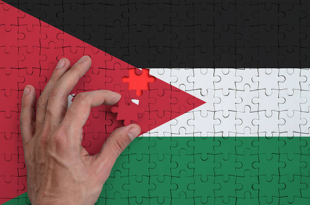 Jordanian lippu on kuvattu palapeli, jonka miehen käsi täydentää taittaa
. - Valokuva, kuva