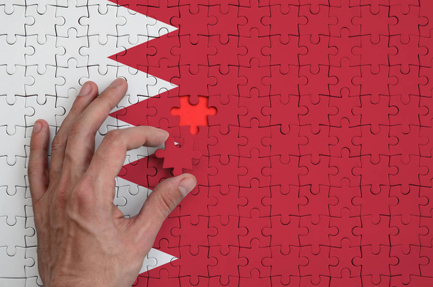 Σημαία του Μπαχρέιν απεικονίζεται σε ένα παζλ, το οποίο ολοκληρώνει το χέρι του άνδρα να πάει πάσο. - Φωτογραφία, εικόνα