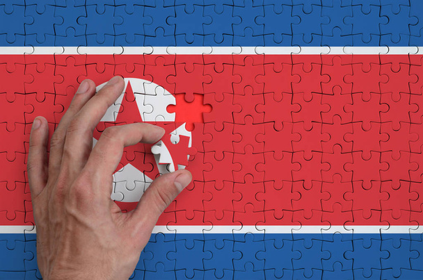 Észak-Korea zászló ábrázol egy puzzle, amely az ember keze befejezi a fold. - Fotó, kép