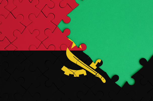 Angola flag  is depicted on a completed jigsaw puzzle with free green copy space on the right side. - Photo, Image