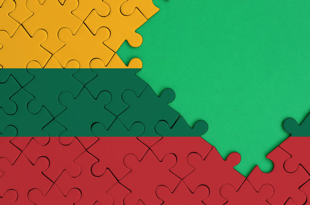 Le drapeau de Lituanie est représenté sur un puzzle terminé avec un espace de copie vert libre sur le côté droit
. - Photo, image