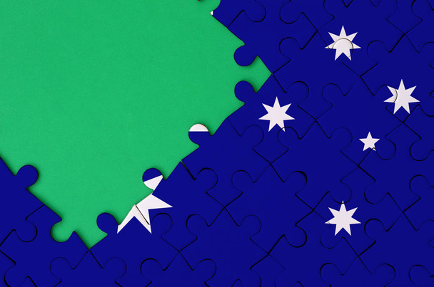 Australia flag  is depicted on a completed jigsaw puzzle with free green copy space on the left side. - Photo, Image
