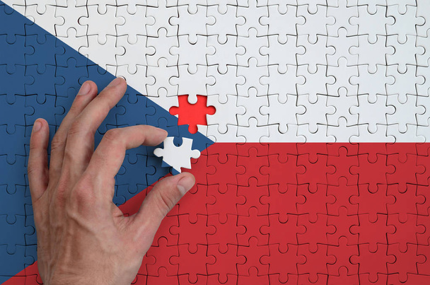Σημαία Τσεχίας απεικονίζεται σε ένα παζλ, το οποίο ολοκληρώνει το χέρι του άνδρα να πάει πάσο. - Φωτογραφία, εικόνα