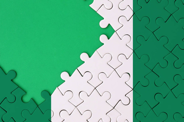 Nigeria-Flagge ist auf einem abgeschlossenen Puzzle mit freiem grünen Kopierraum auf der linken Seite abgebildet. - Foto, Bild