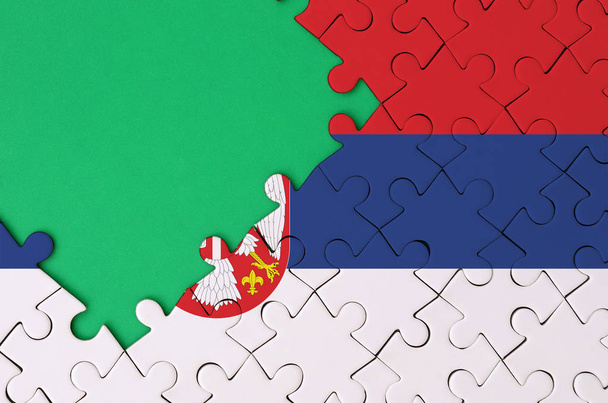 Die serbische Flagge ist auf einem abgeschlossenen Puzzle mit freiem grünen Kopierplatz auf der linken Seite abgebildet.. - Foto, Bild